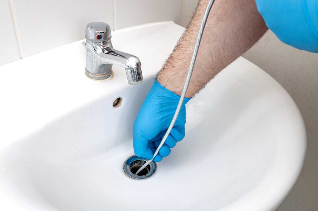 Plumber snaking a bathroom sink drain