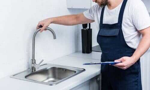 Plumber inspecting a kitchen sink faucet