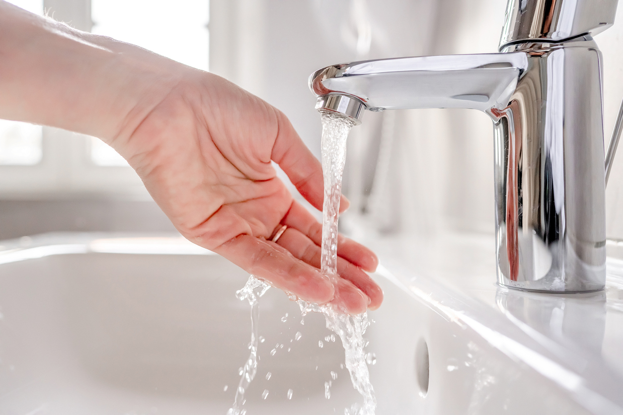 Young woman washes her hands with soap over the sink