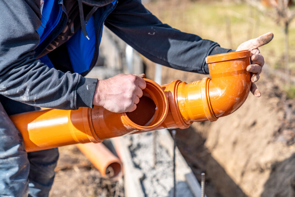 Plumber laying orange PVC drain pipes for a plumbing installation